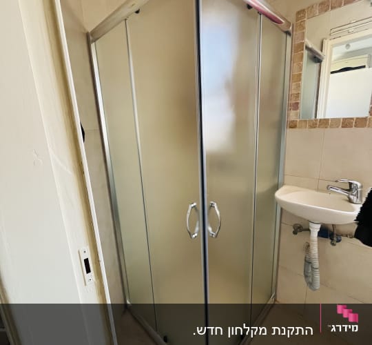 מקלחון פינתי עם דלתות זכוכית וכיור קטן לידו